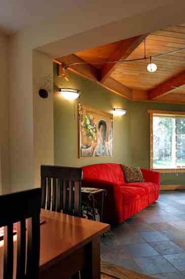 AFTER: The living room, kitchen and dining areas create an open, inviting space for entertaining. The dark, slate floor absorbs solar heat and radiates it through the space on winter nights.